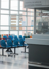 An empty hospital lobby with chairs and a desk
