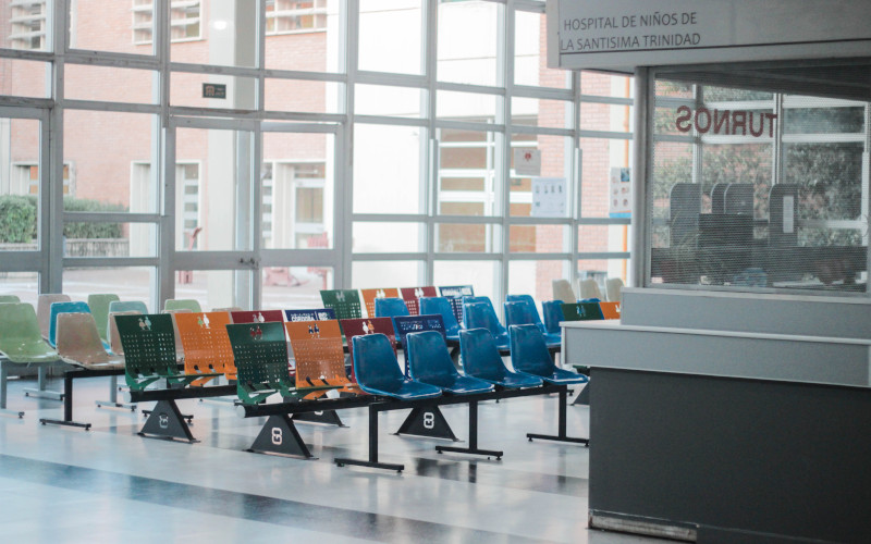 An empty hospital lobby with chairs and a desk