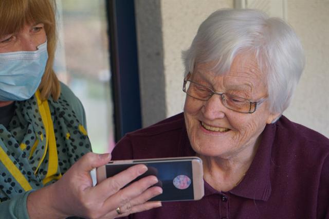 masked woman showing elderly woman an iphone