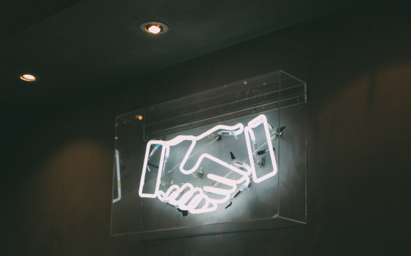 neon sign of two hands shaking