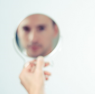 A hand mirror showing a man
