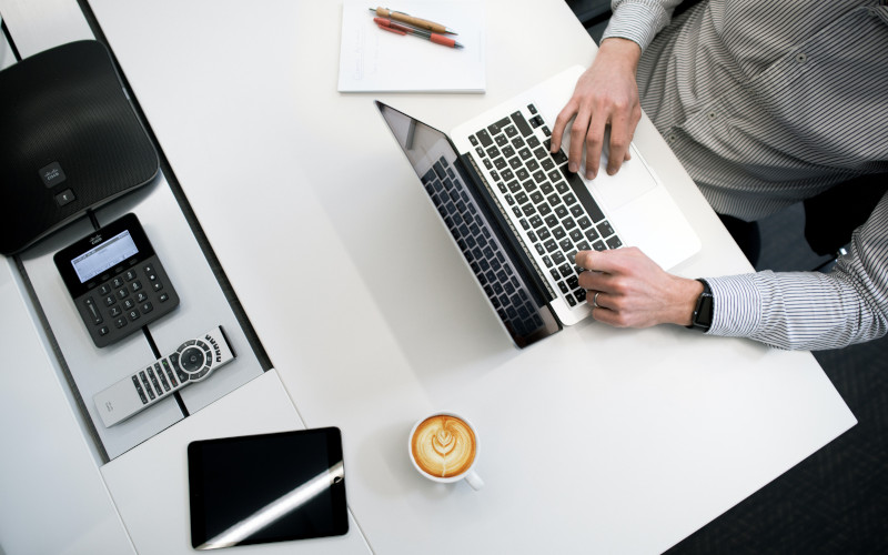 Man typing on laptop with coffee