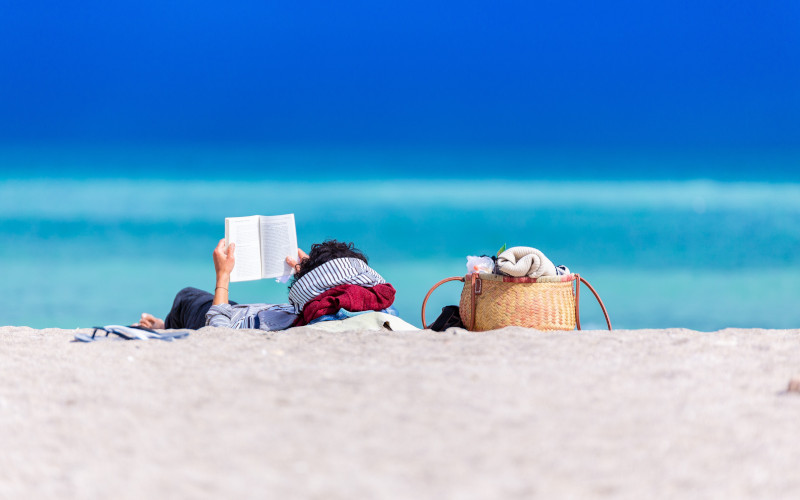 Man reading a book on a beach