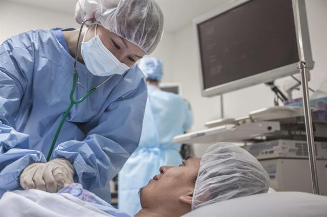 A surgeon stands over a patient