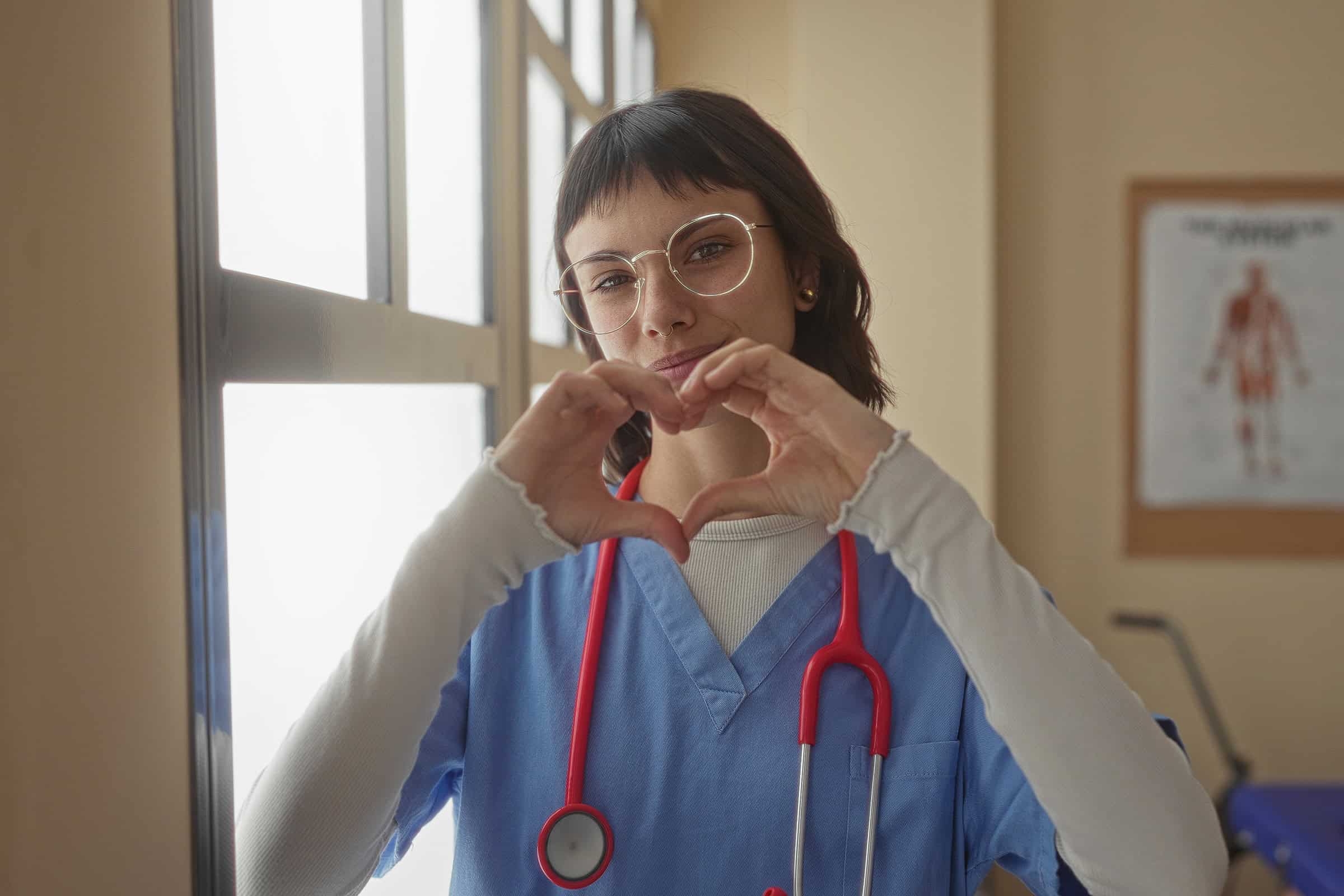 Nurse smiling and making a heart with her hands