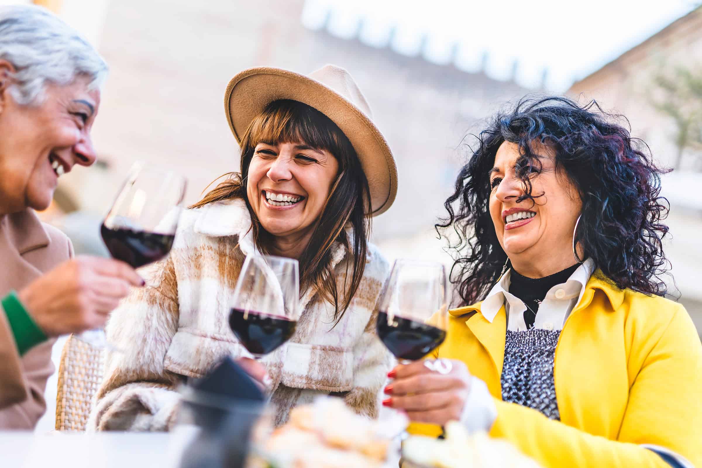 Happy women drinking and toasting red wine outdoors