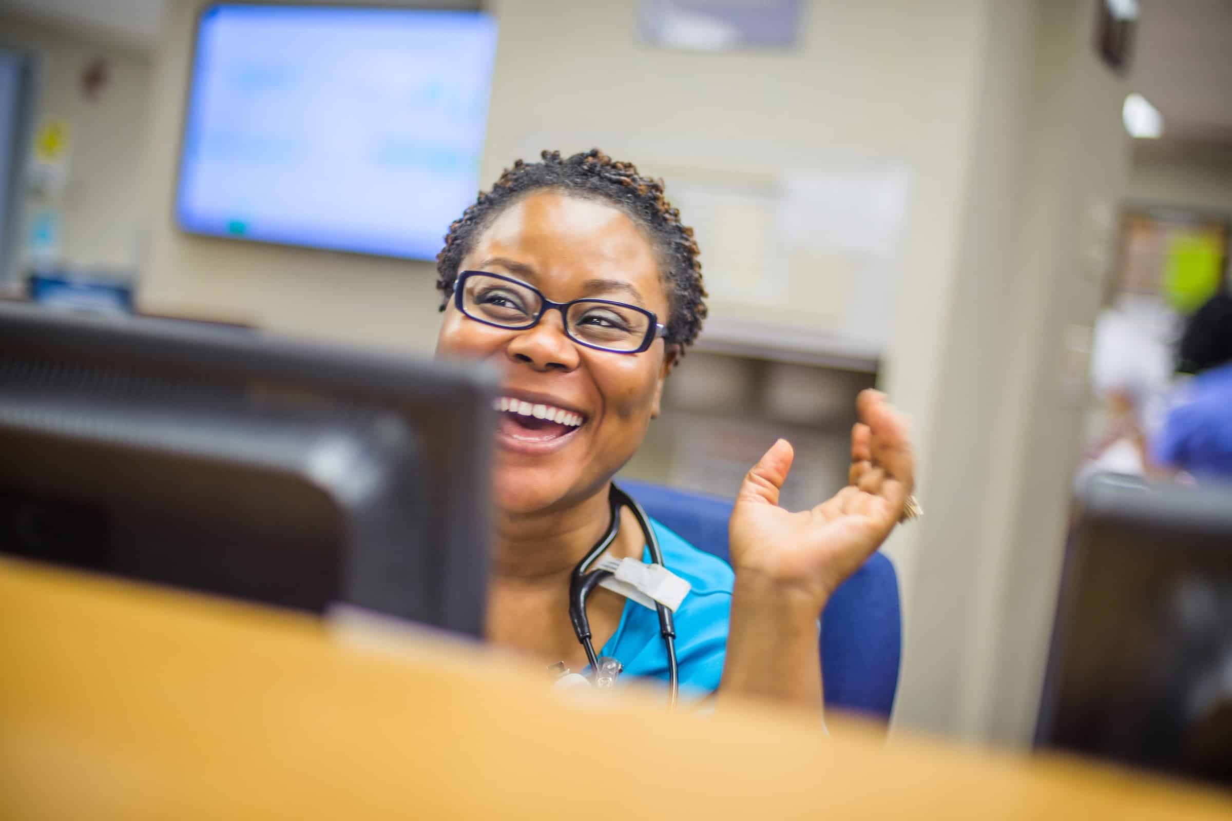 A nurse smiling in front of a computer