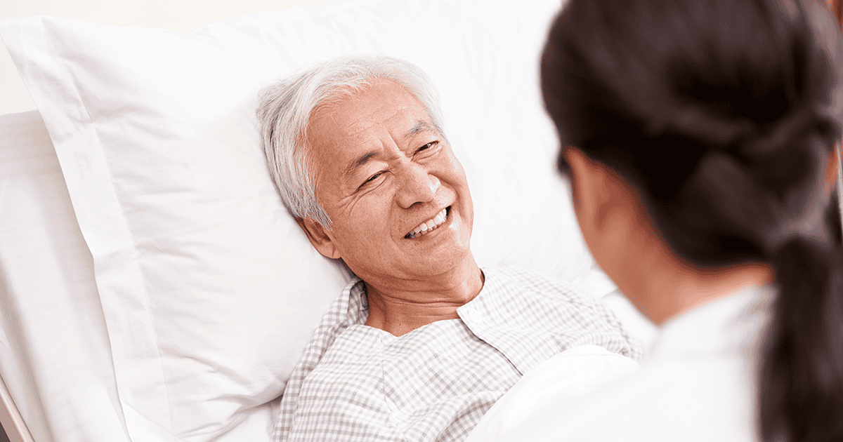 A patient in a hospital bed smiling at a doctor