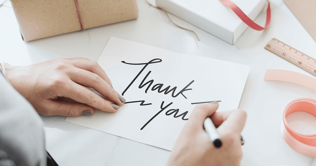 Hands writing a thank-you note