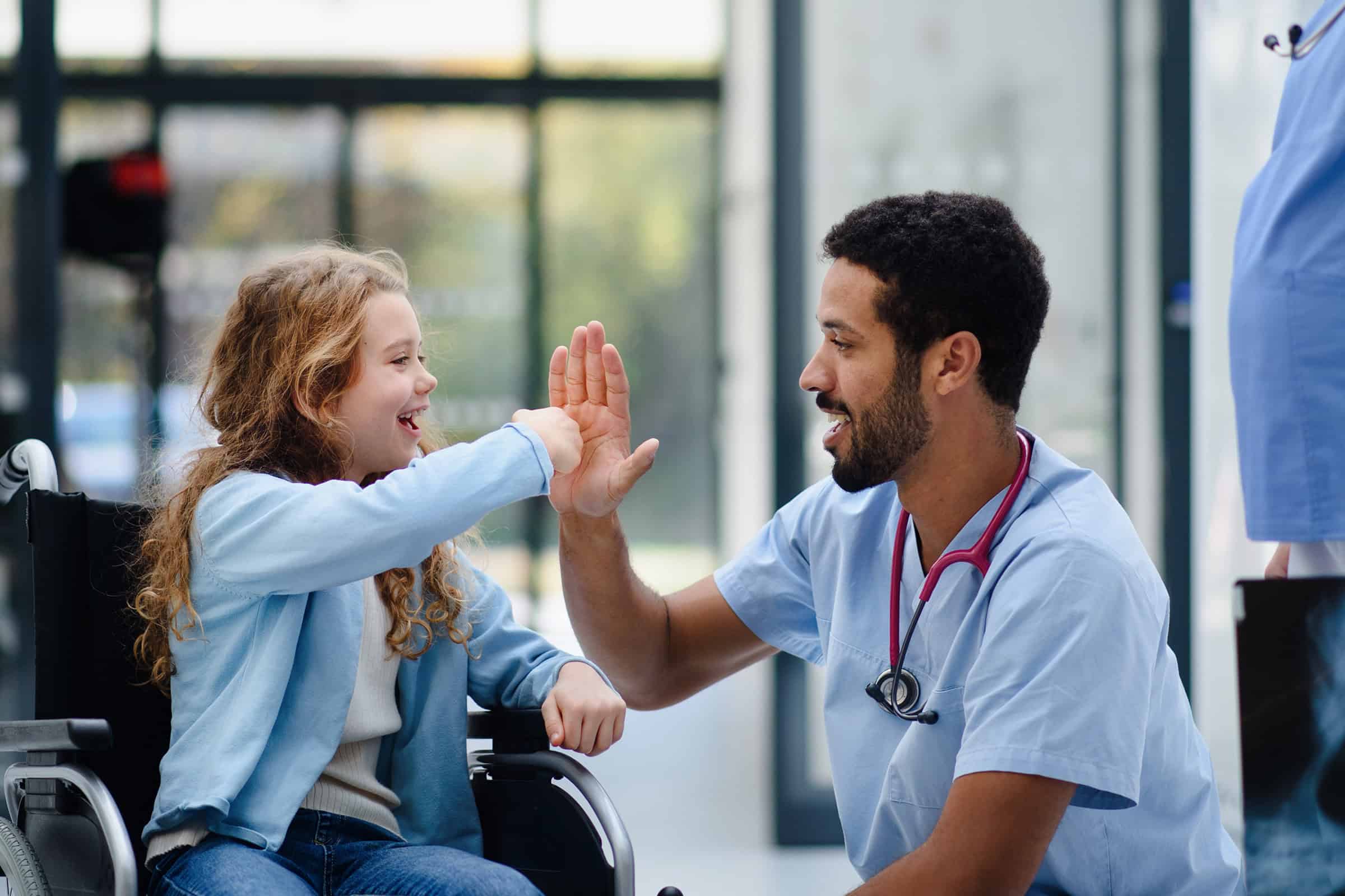 Doctor having fun with a little girl in a wheelchair