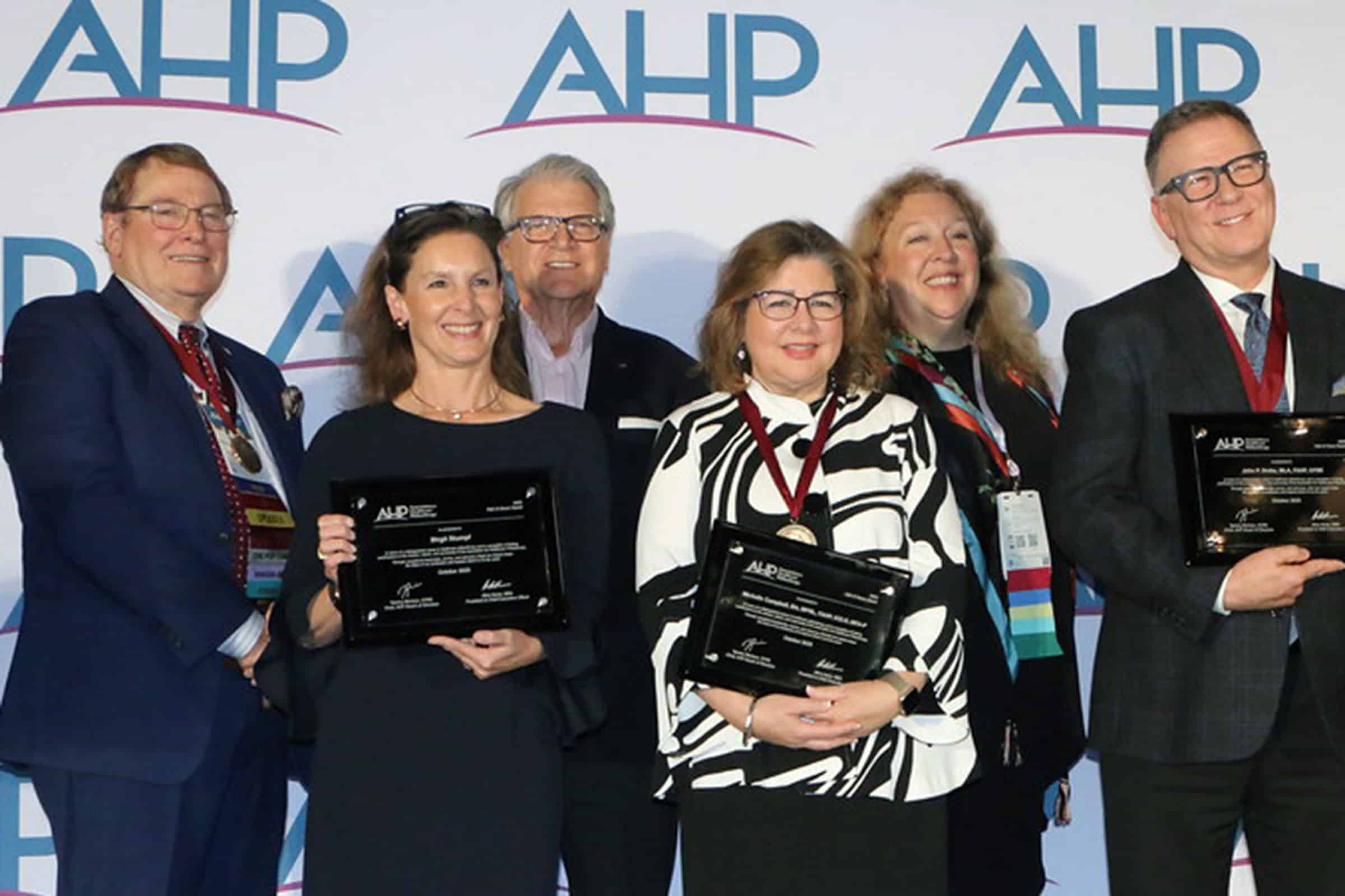 A group of people smiling and holding plaques