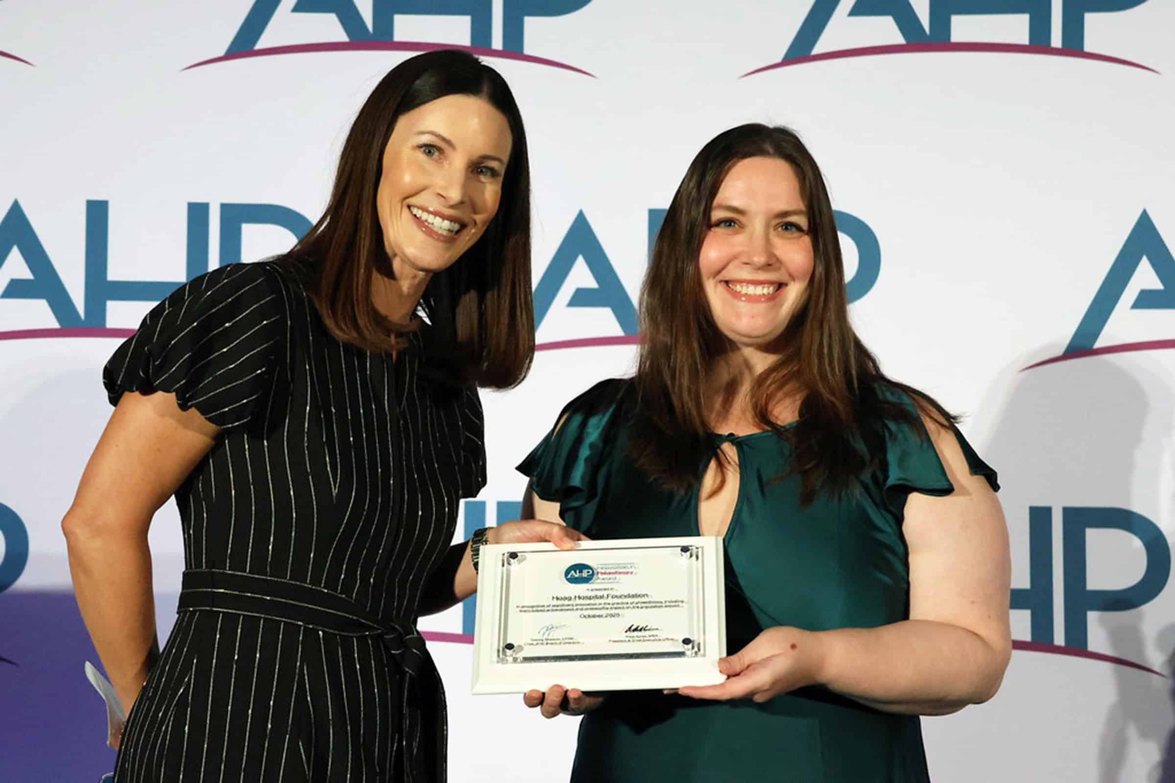 Two women smiling and holding a plaque