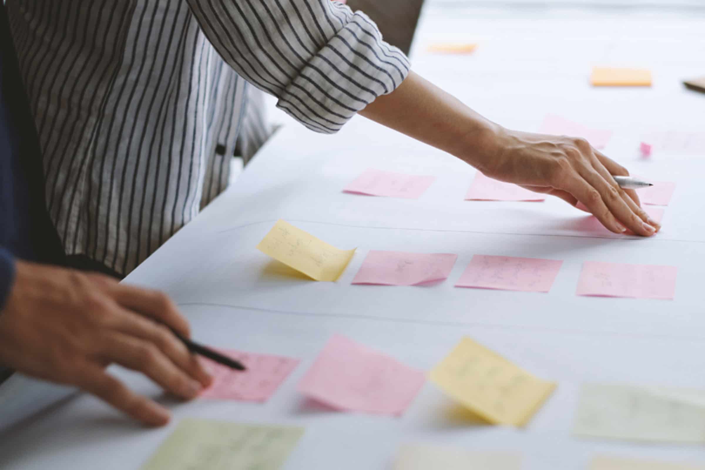 person putting sticky notes on a table